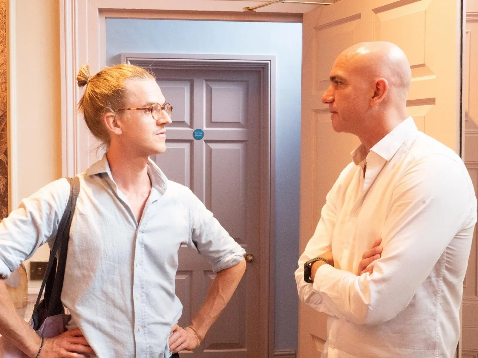 Two men in light shirts talking in a doorway